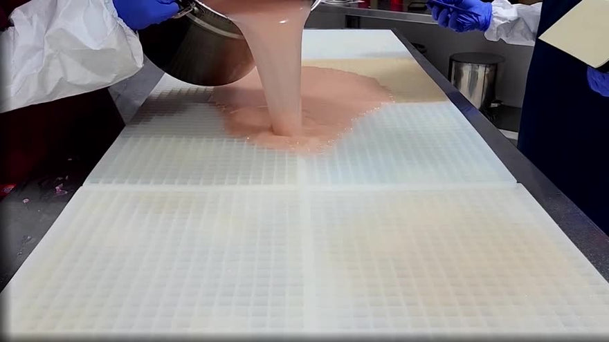 Gummy mixture being poured across a commercial silicone gummy mold during production