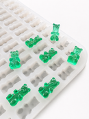 Molde para gomitas de osito de 1.5 mL - 296 cavidades - primer plano en ángulo, con muestras de gomitas verde esmeralda, translúcidas