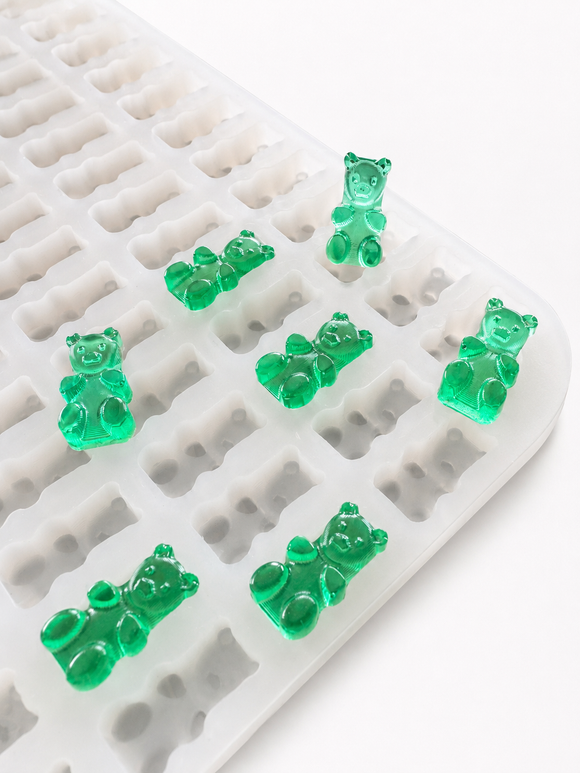 Molde para gomitas de osito de 1.5 mL - 296 cavidades - primer plano en ángulo, con muestras de gomitas verde esmeralda, translúcidas