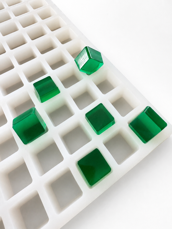 Angled view of the 2.85mL cube gummy mold with 315 cavities and translucent emerald green gummy samples